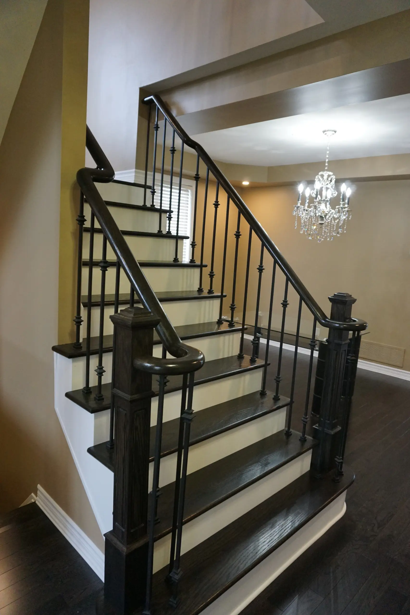 A bold curved staircase featuring dark wood treads, matching handrails, and vertical black balusters.