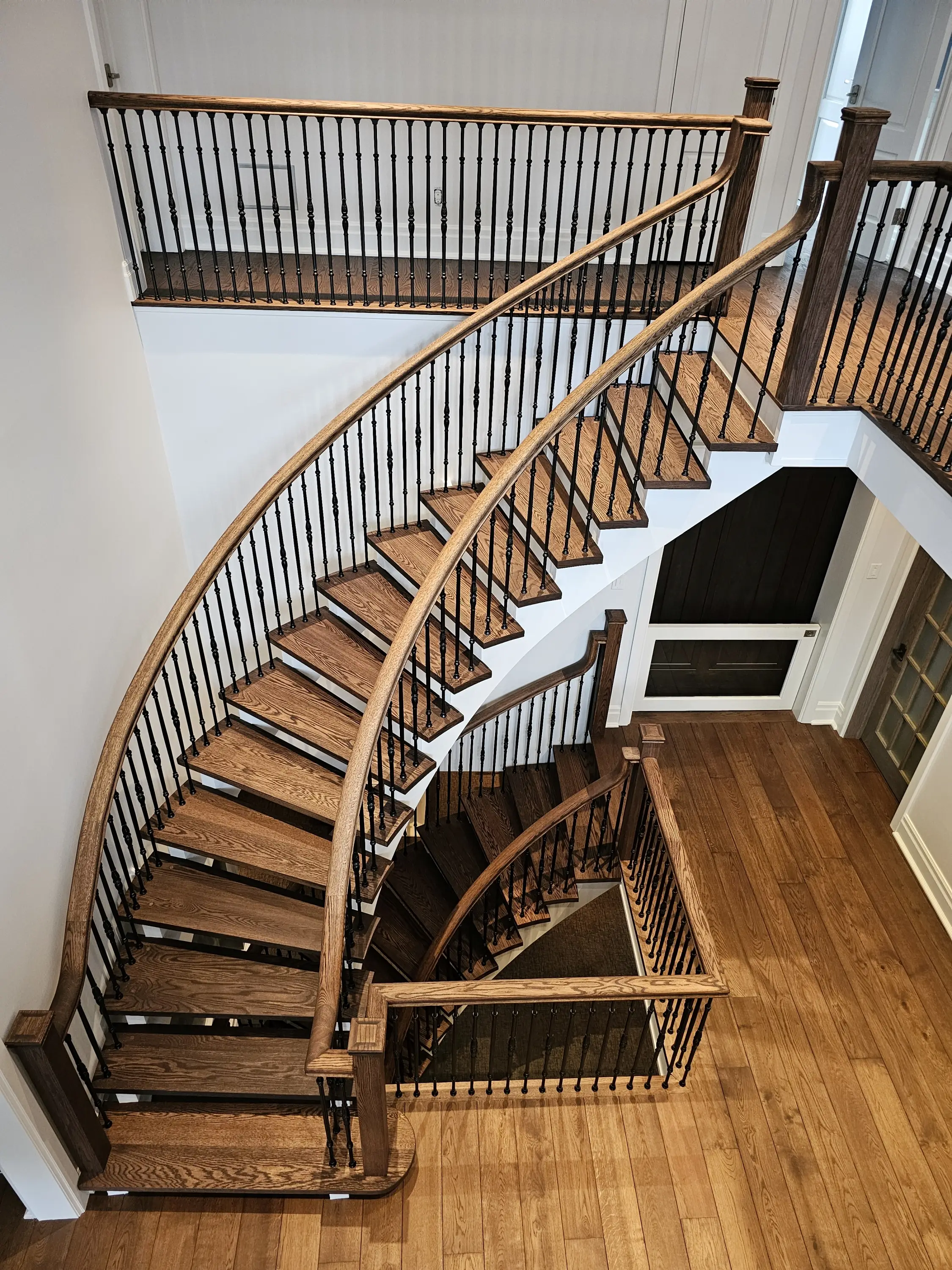 A spiral staircase with rich wood steps and sleek black railings, combining elegance and functionality.