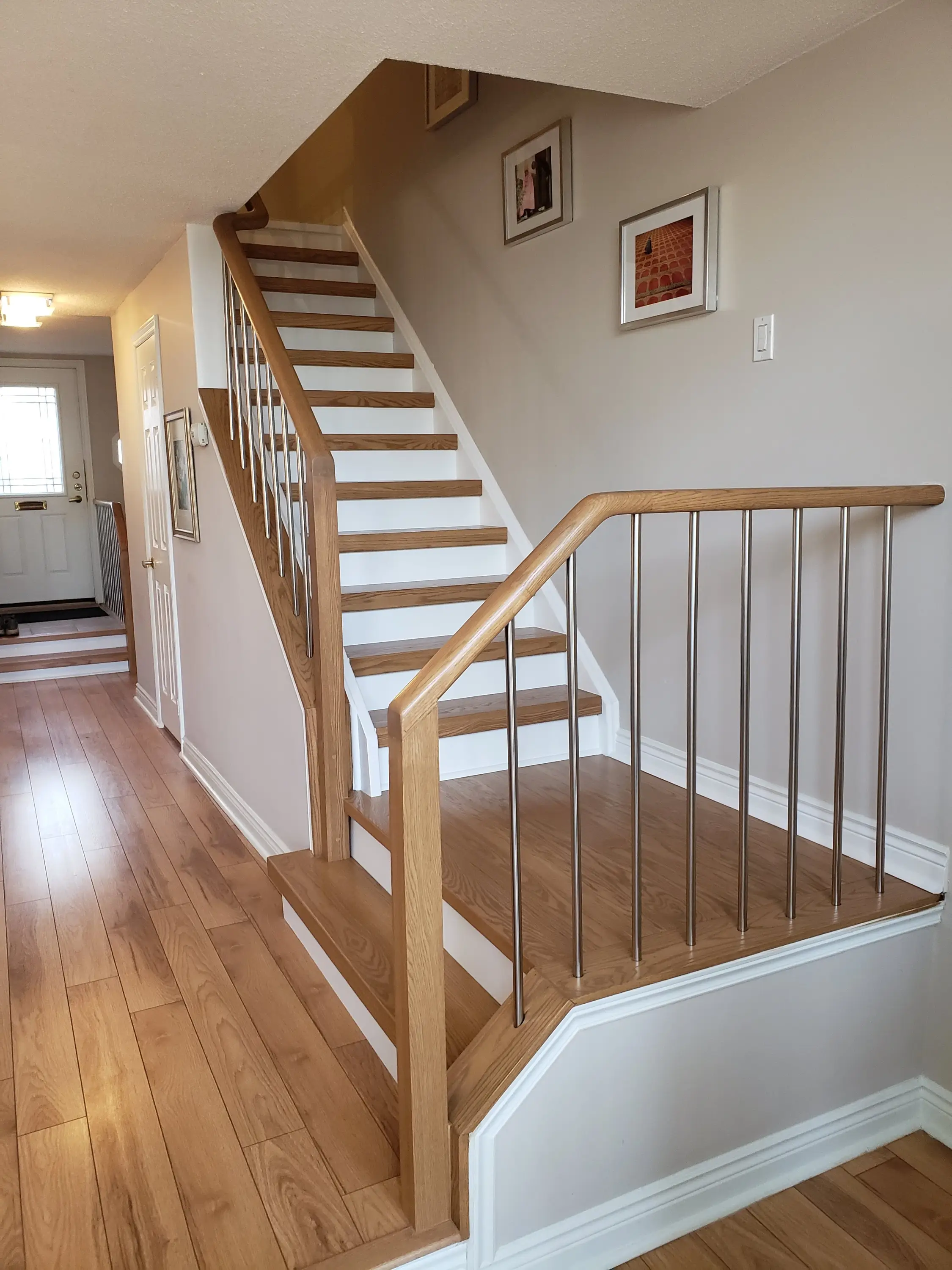 Light wood stairs with slim metal balusters and white risers, seamlessly integrated into a minimalist hallway.