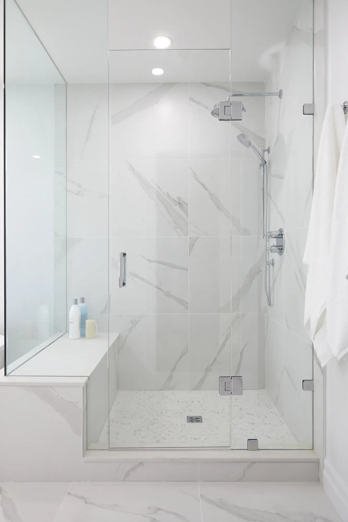 A renovated bathroom with a double vanity, light wood cabinets, white countertops, and modern lighting for a personalized and functional space.