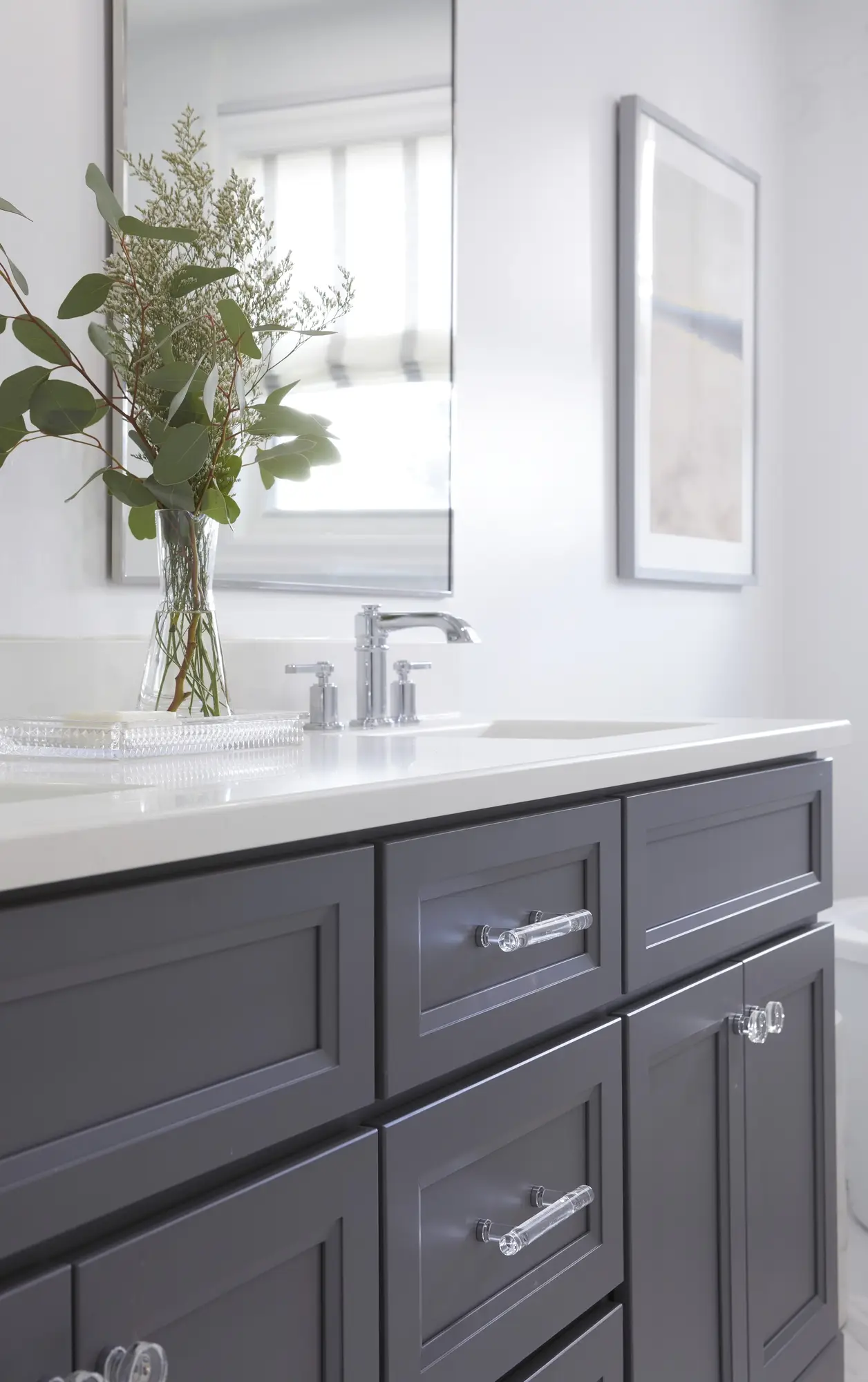 A renovated bathroom with a modern vanity, round mirror, and sleek fixtures.