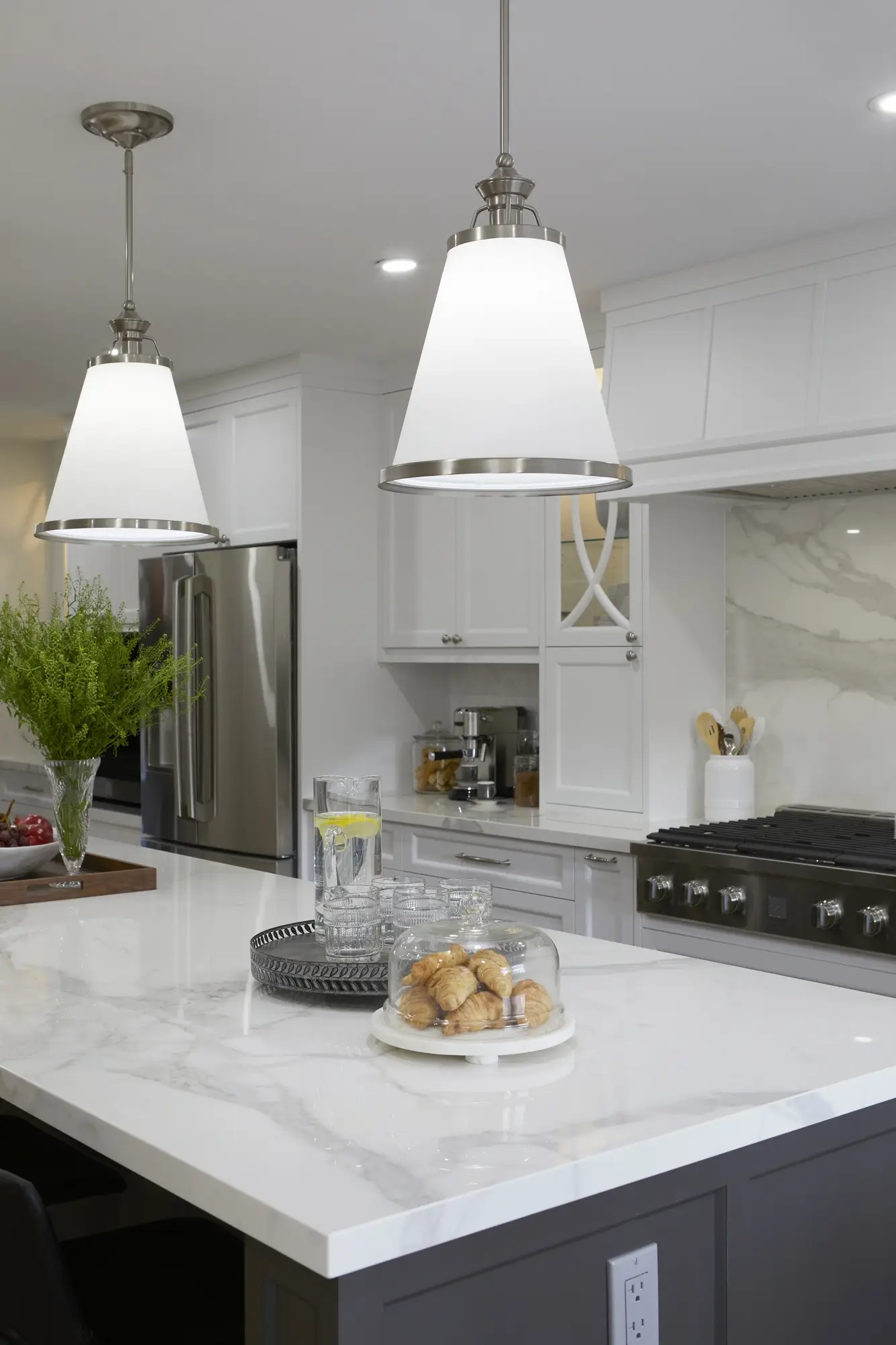 A bright kitchen with white shaker cabinets, quartz counters, and stainless steel appliances.