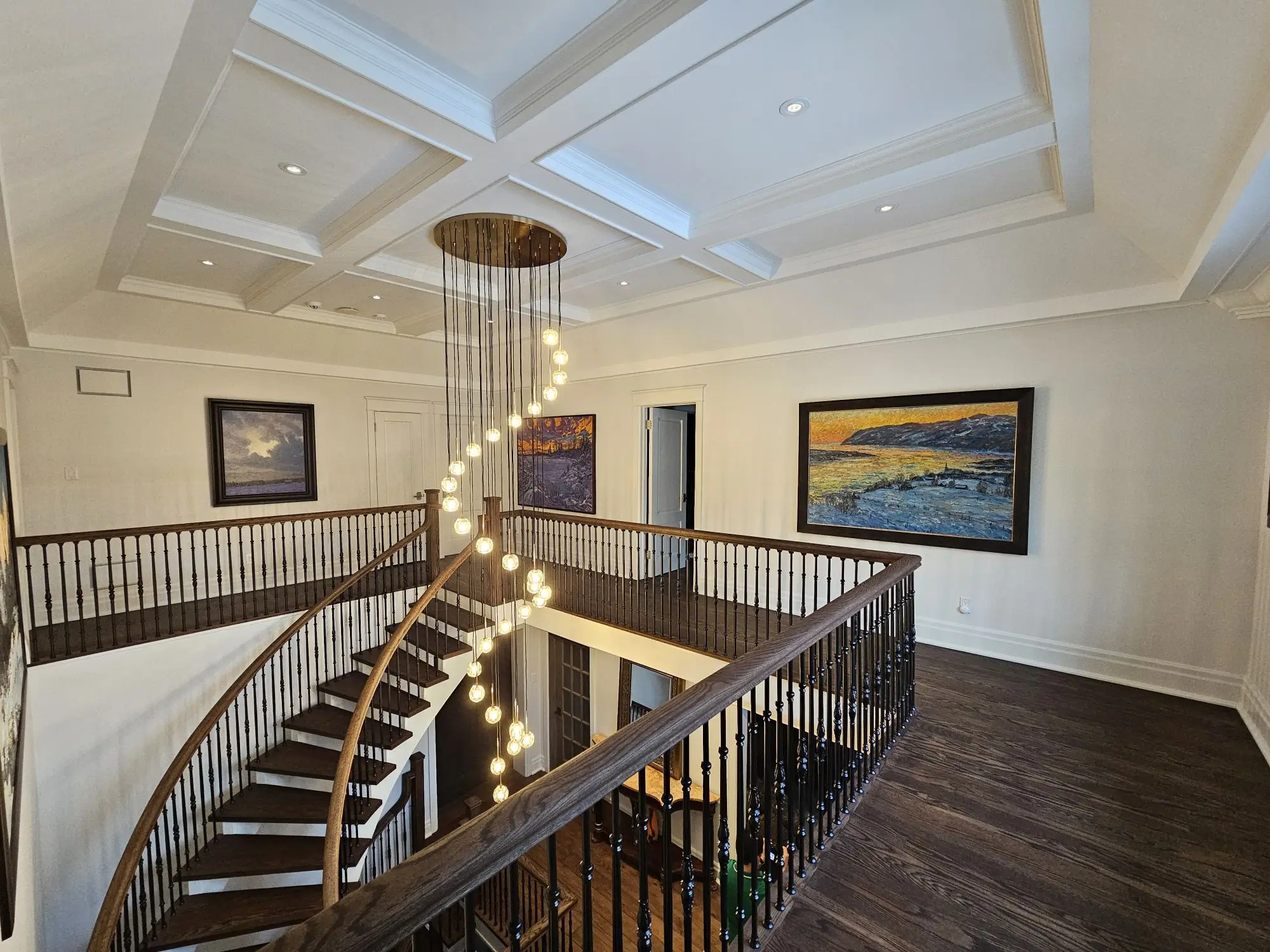 Curved interior staircase with oak treads, white risers, and custom iron railings renovated by Strataline in Vaughan.
