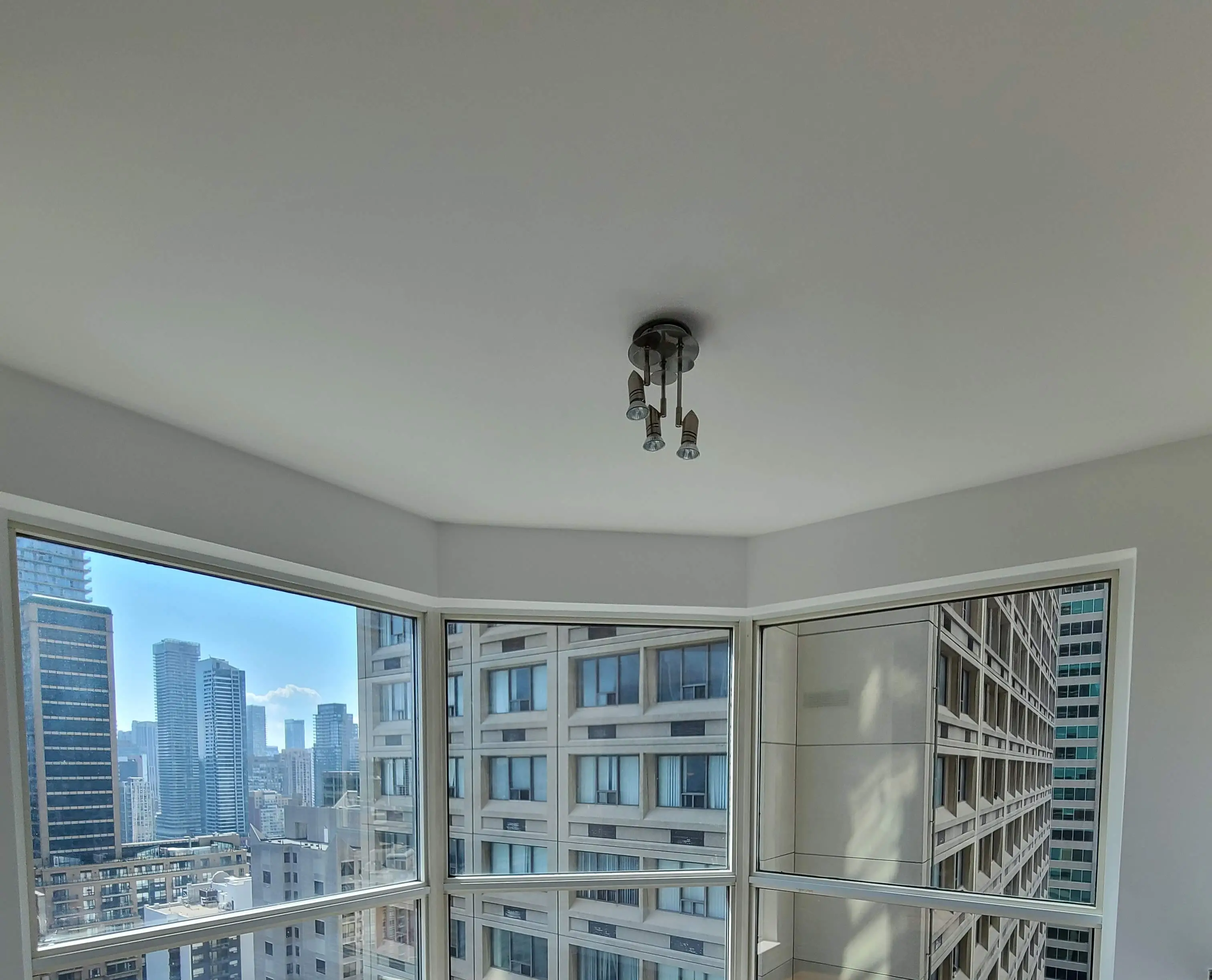 A freshly renovated room with smooth, dust-free ceilings, large windows letting in natural light, and furniture carefully covered for protection during the process.