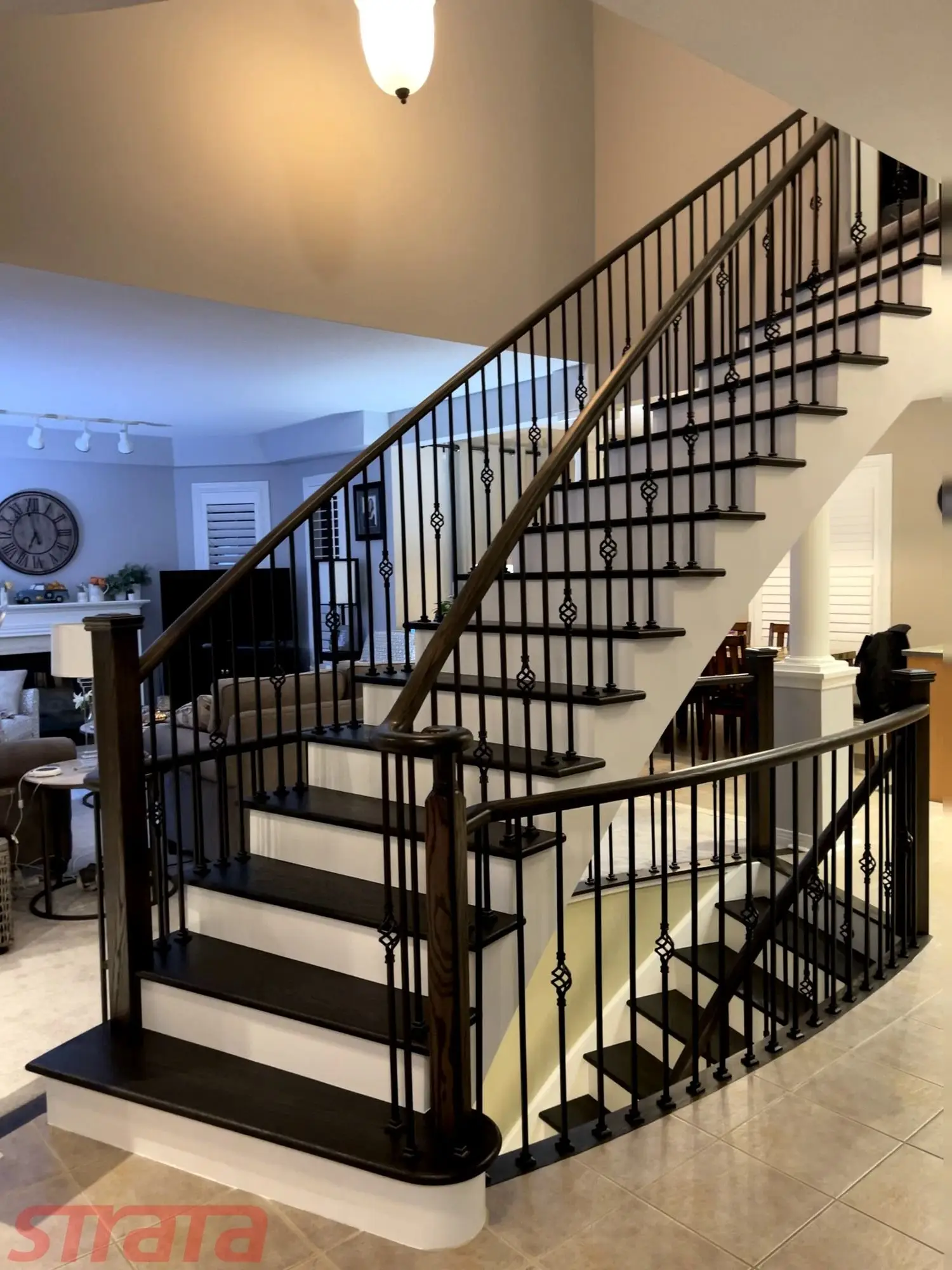 Curved staircase with oak stair tread caps and black iron balusters installed in Toronto.