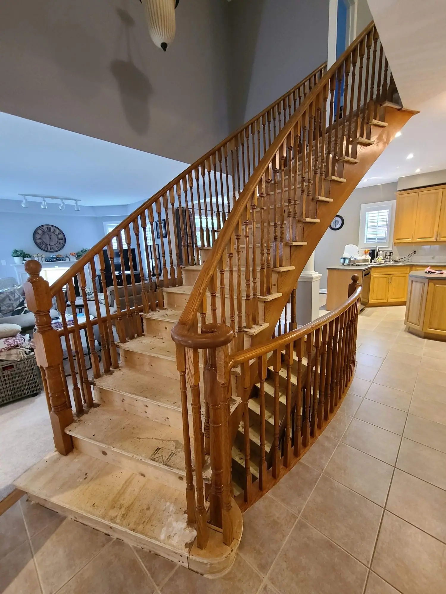 Curved staircase in Toronto after carpet removal showing raw wood treads before stair capping.