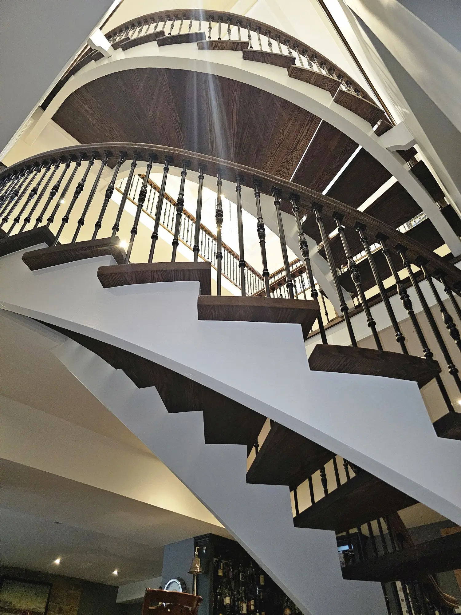 Curved staircase refinishing in Toronto with dark treads and iron railing.