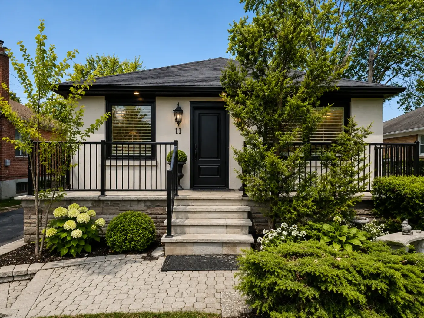 GTA exterior house painting with refreshed stucco, black trim, painted garage doors, and updated curb appeal.