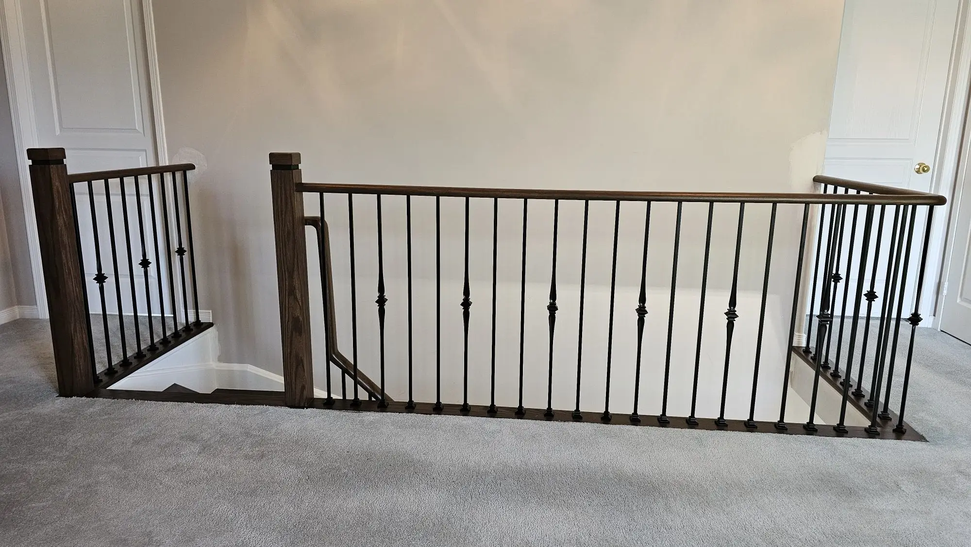 Stair railing installation in Mississauga with black balusters.