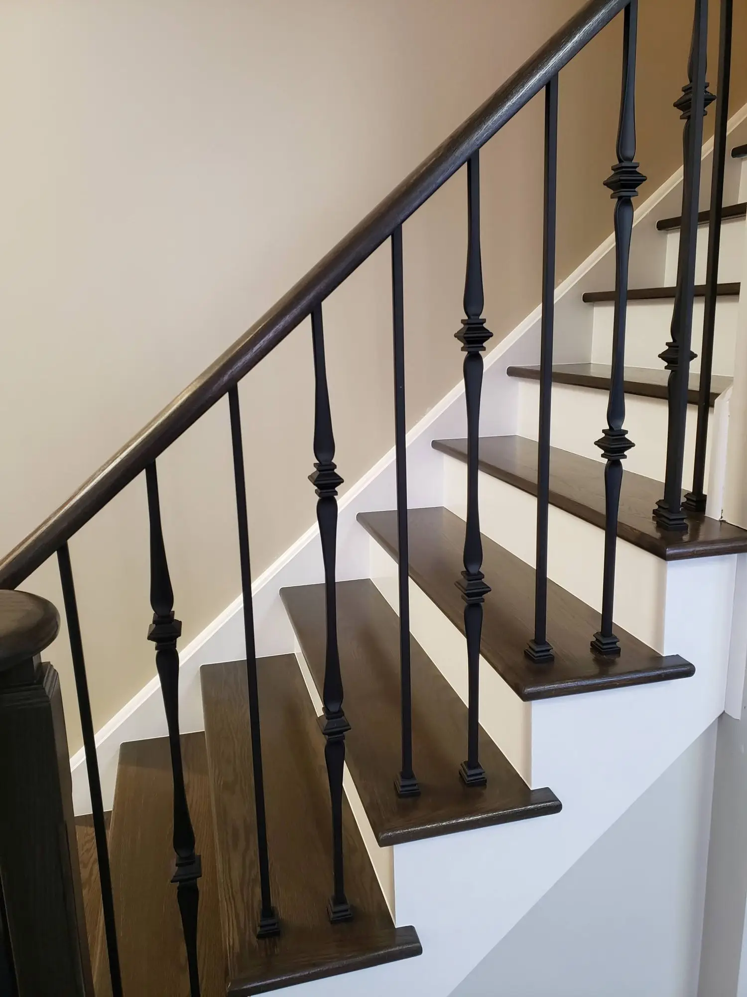 Stair railing installation in Toronto with black balusters and wood stairs.
