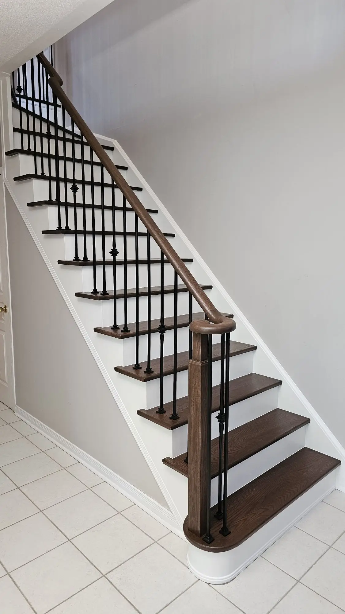Black balusters with wood handrail on a stair railing installation in Toronto.