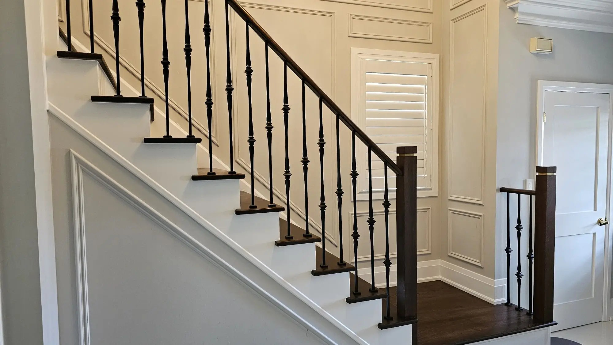Modern stair railing installation in Vaughan with black balusters and wood handrail.