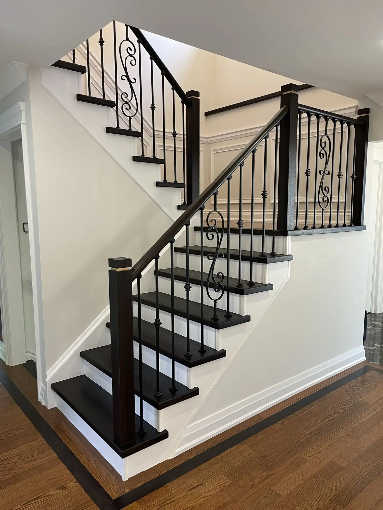 Staircase refinishing in Toronto with iron railing and dark treads.