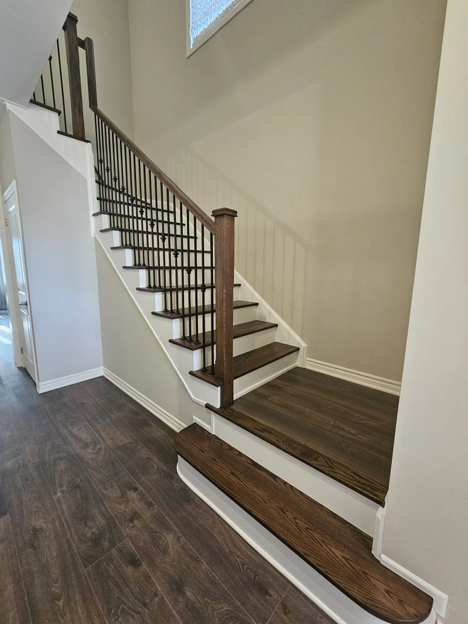 Staircase refinishing in Woodbridge with dark wood and iron balusters.