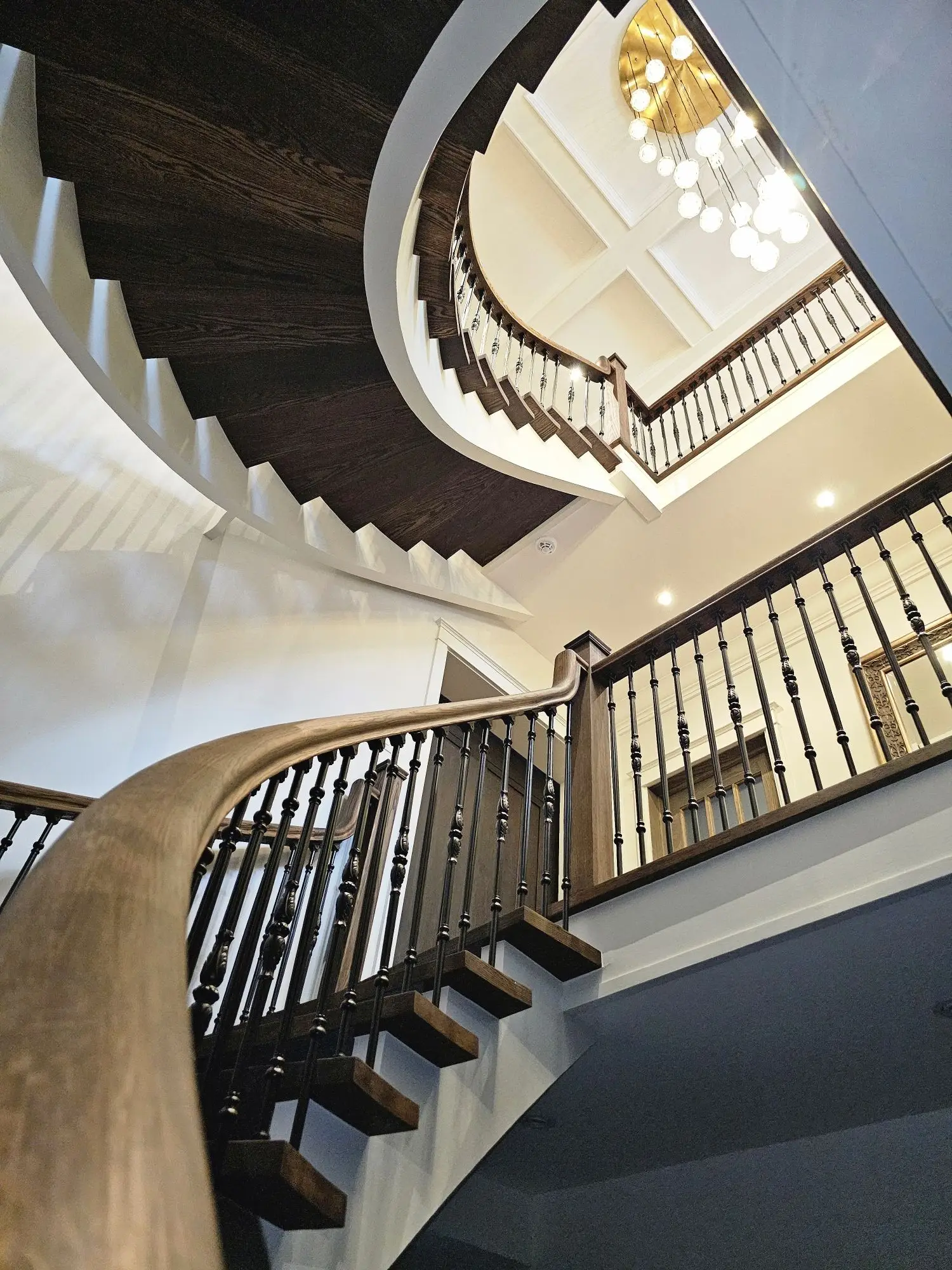 Spiral staircase renovation in Toronto with iron railing.