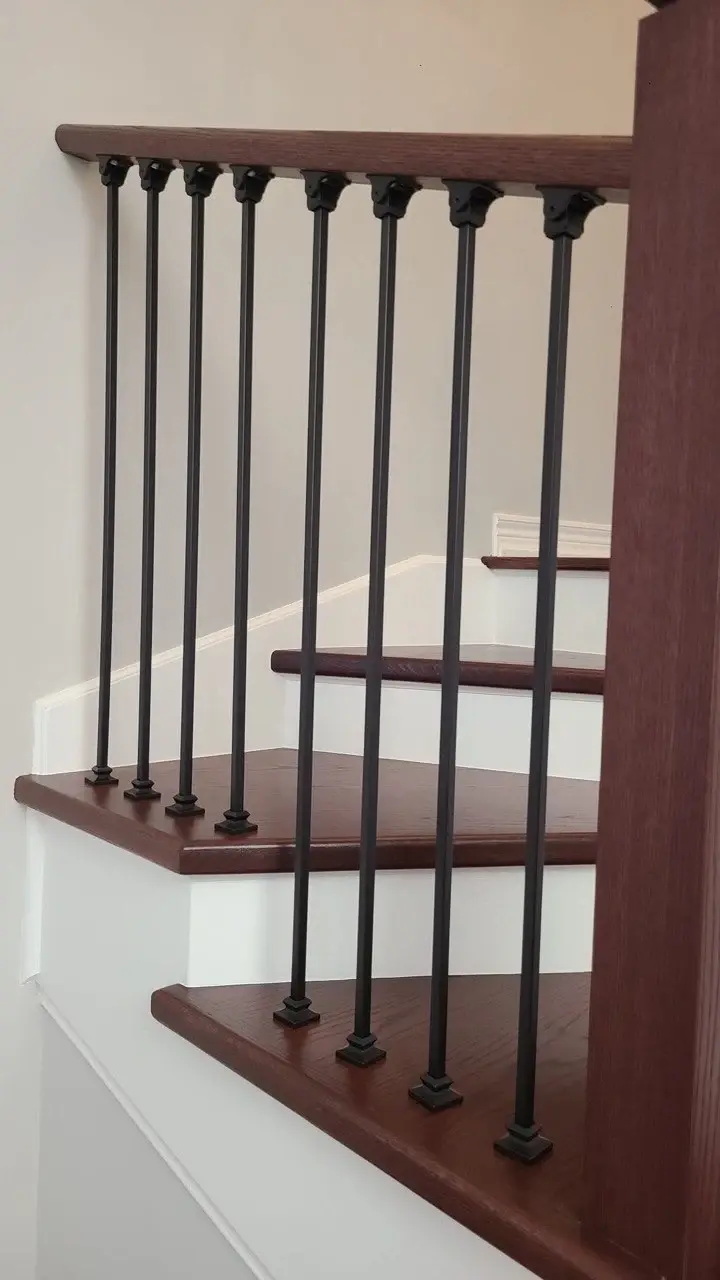 Renovated stair landing with dark-stained wood treads and black metal balusters.