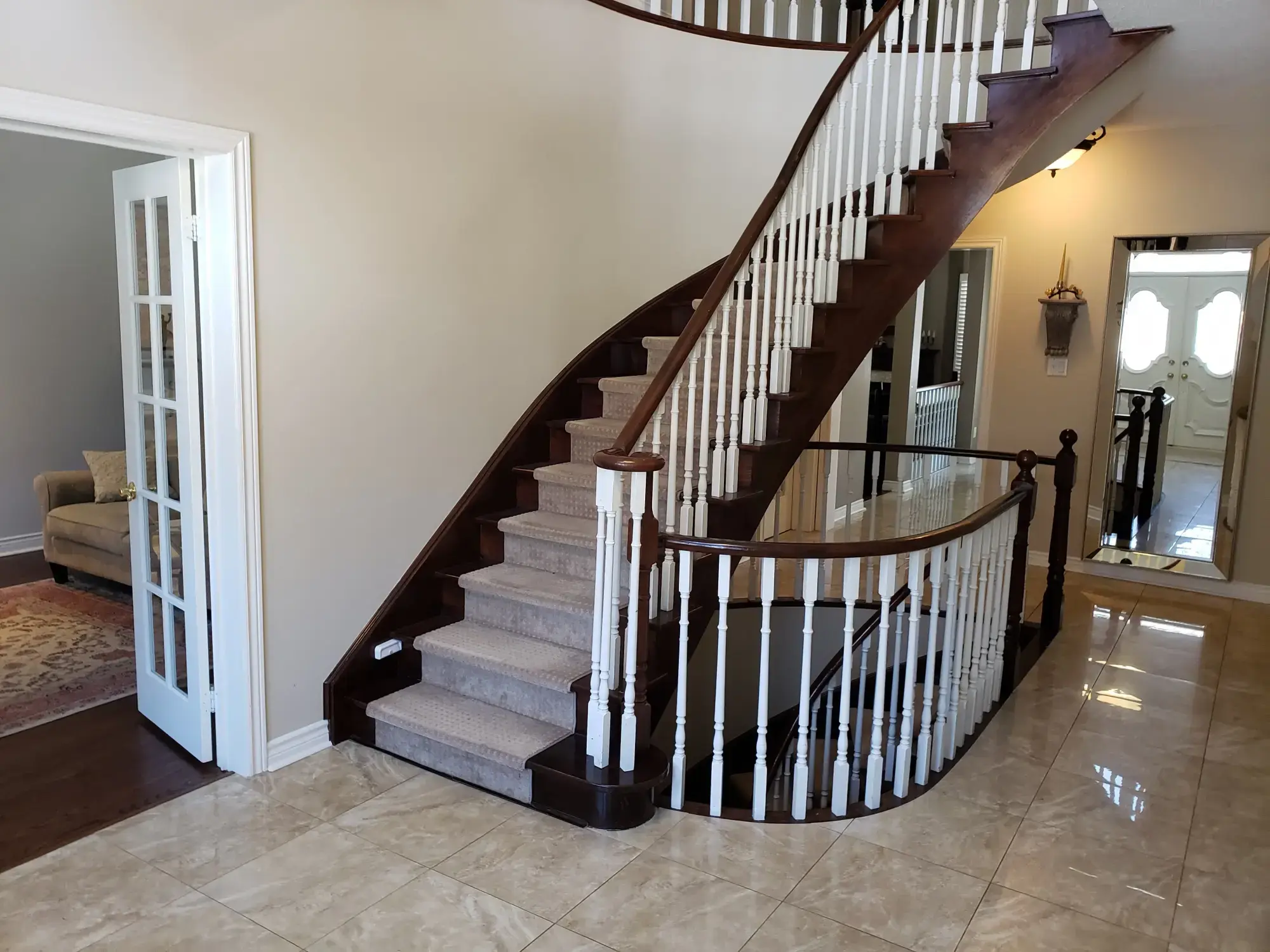 Curved staircase before refinishing with white wood spindles and worn stair finishes.