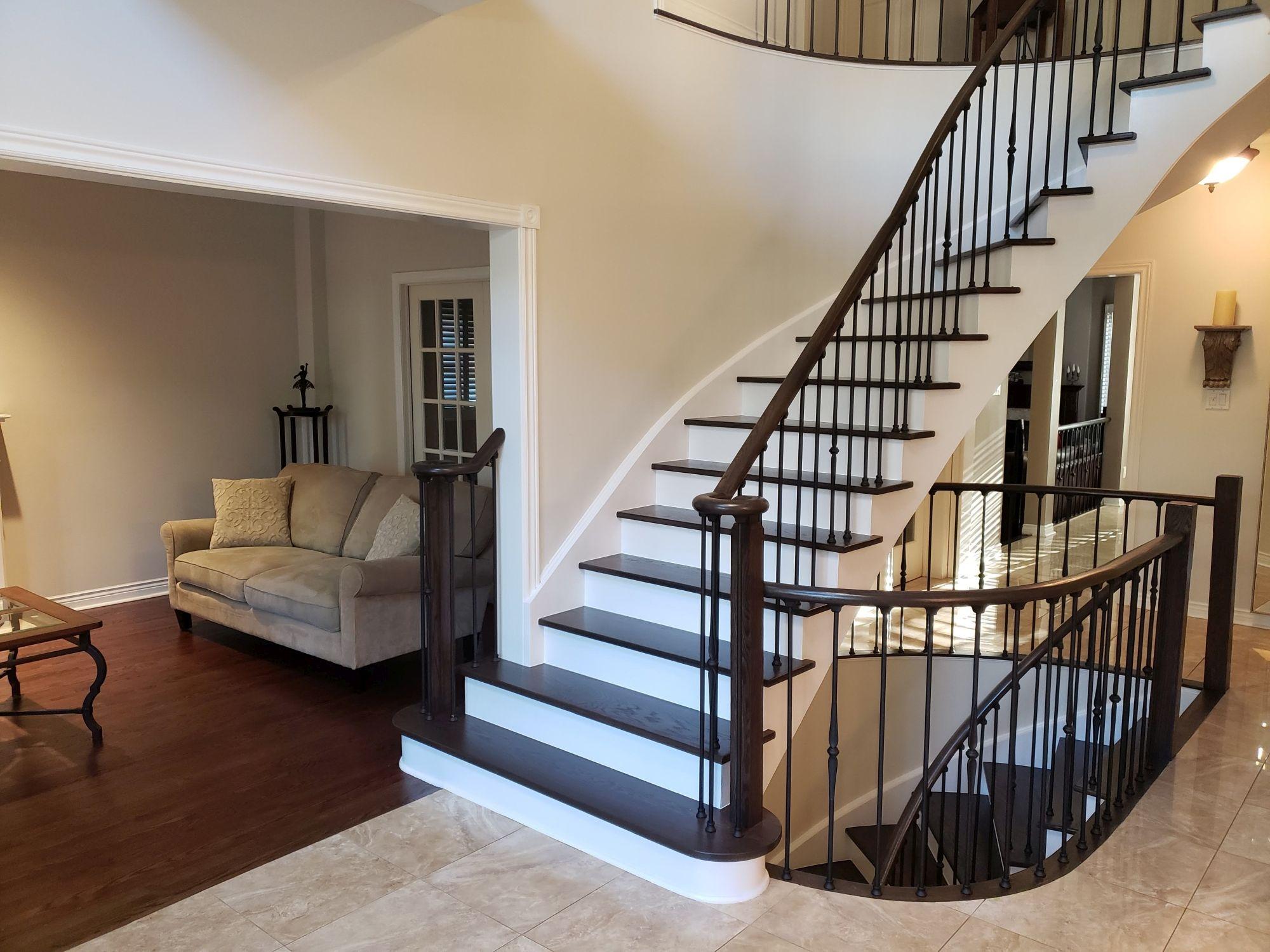 Toronto staircase renovation with hardwood treads and black iron railings.