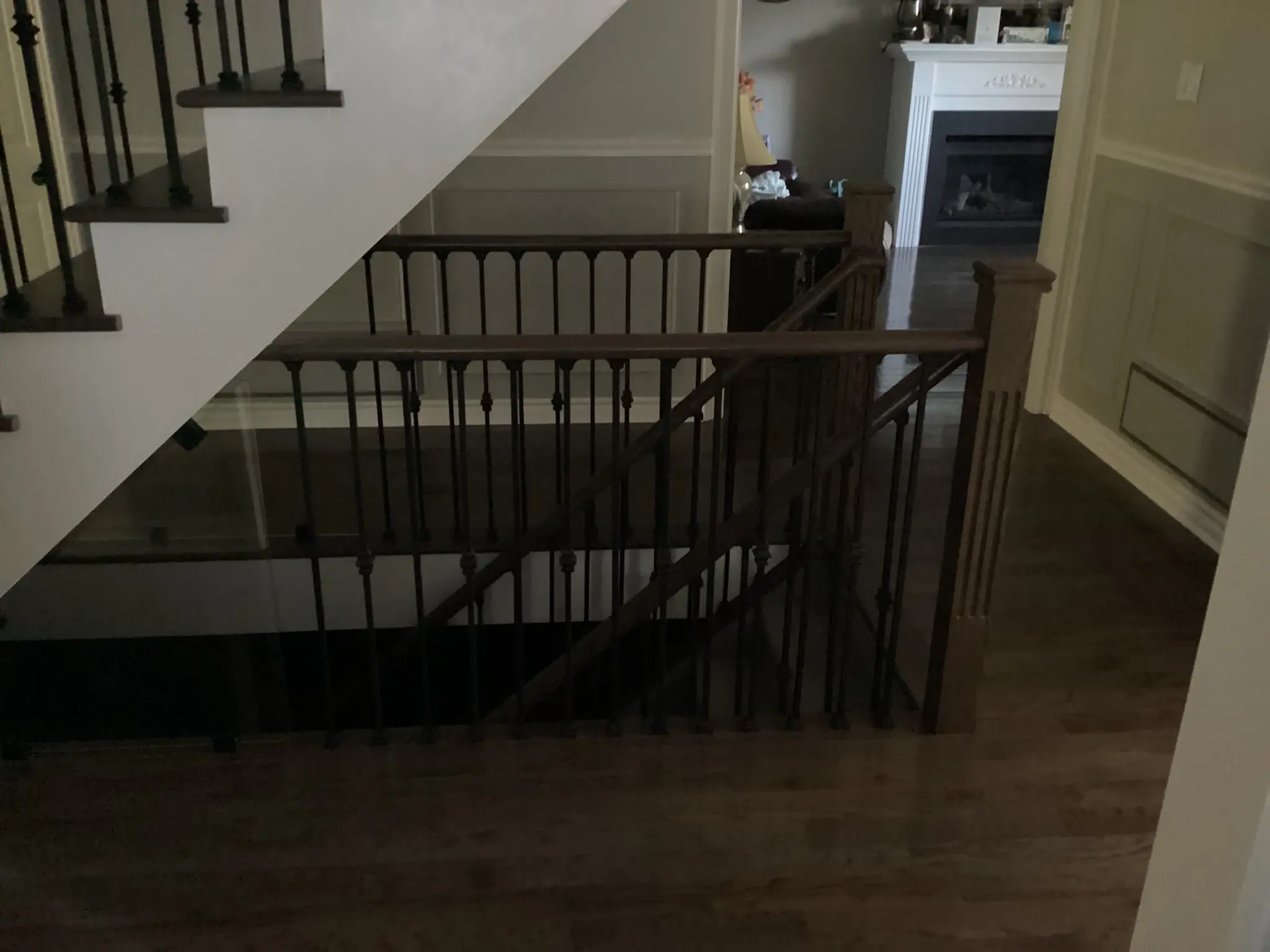 Upper stair landing after renovation with dark wood flooring and black iron railings.