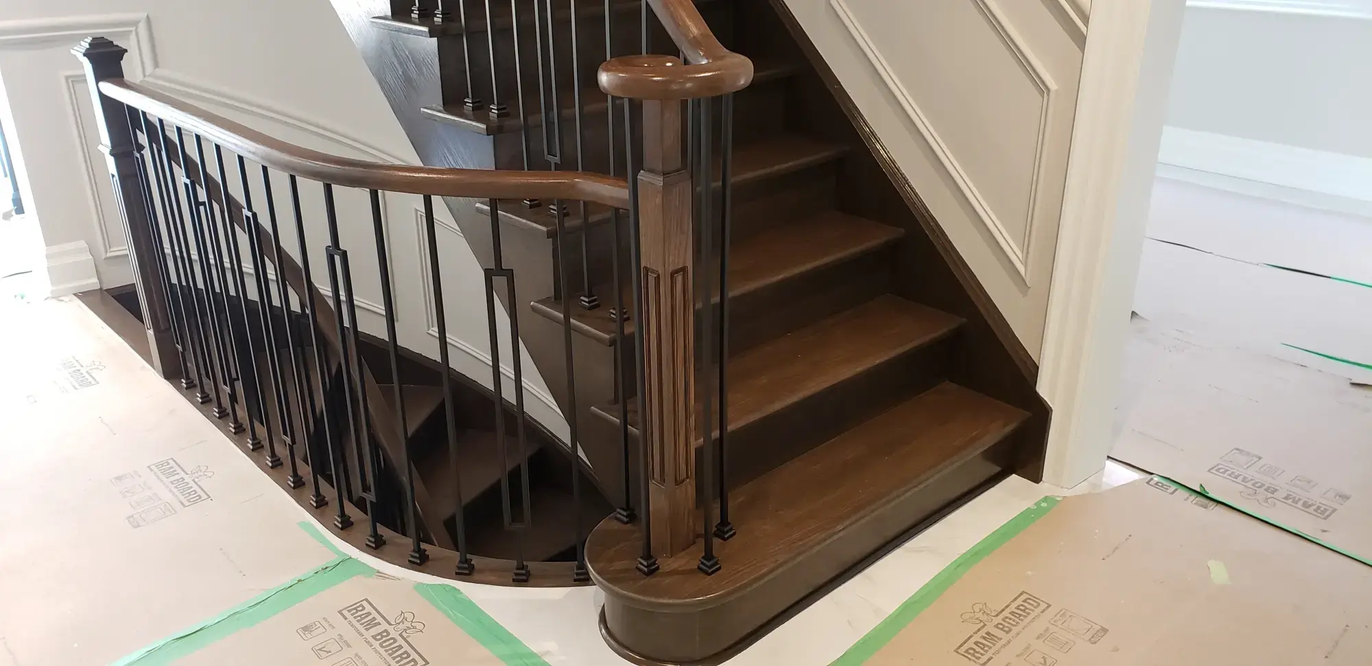 The same Woodbridge staircase after dark refinishing and black metal baluster installation.