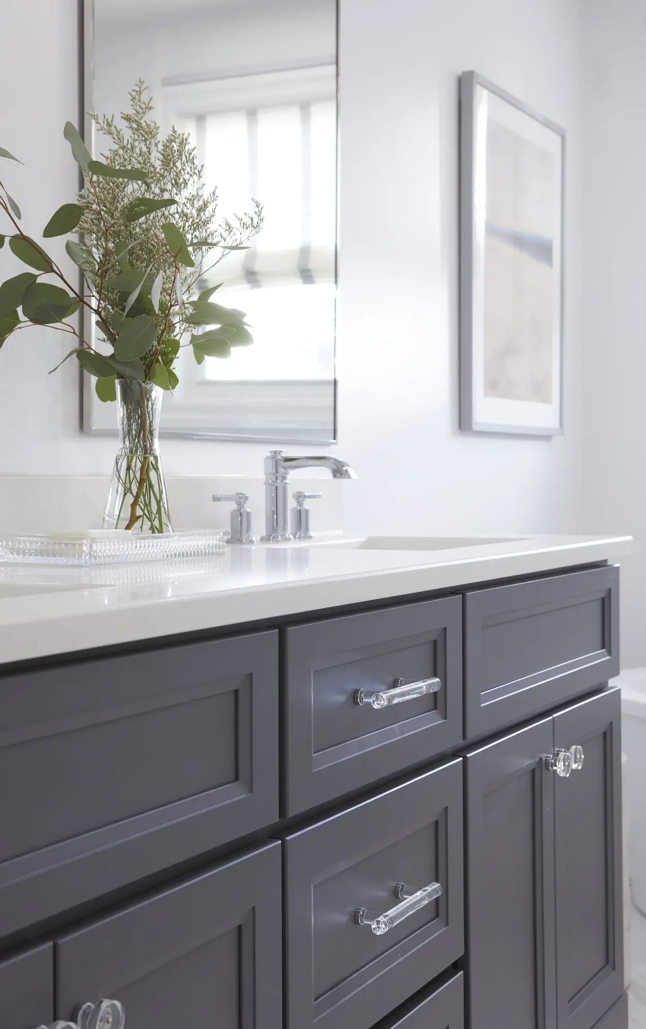 A renovated bathroom with a modern vanity, round mirror, and sleek fixtures.