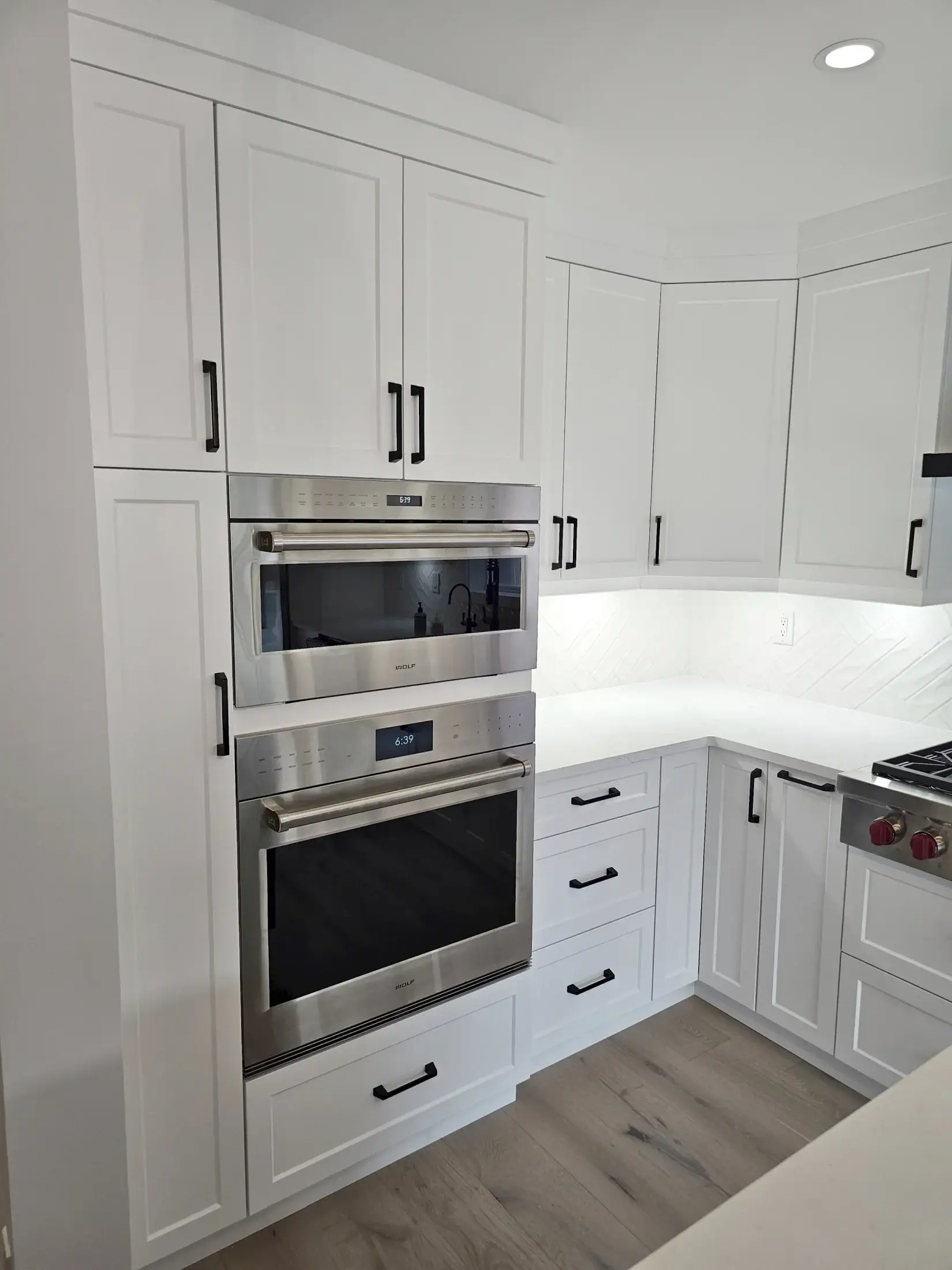 Built-in wall ovens set into white shaker kitchen cabinetry with black hardware and bright task lighting in Vaughan.