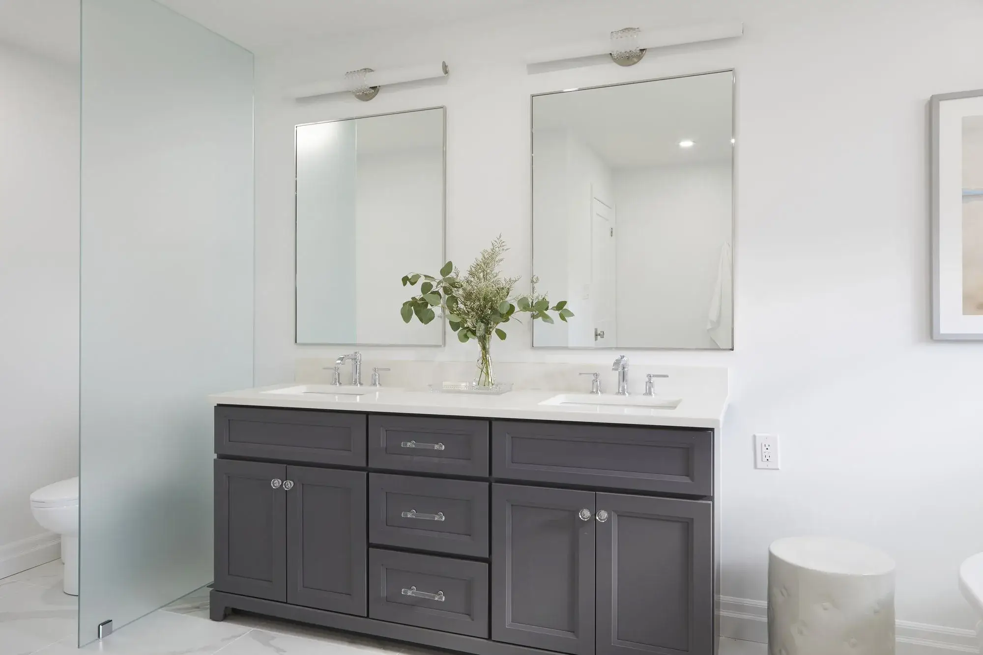 Dark double vanity bathroom renovation with two mirrors, white countertop, integrated storage, and modern lighting in Vaughan.