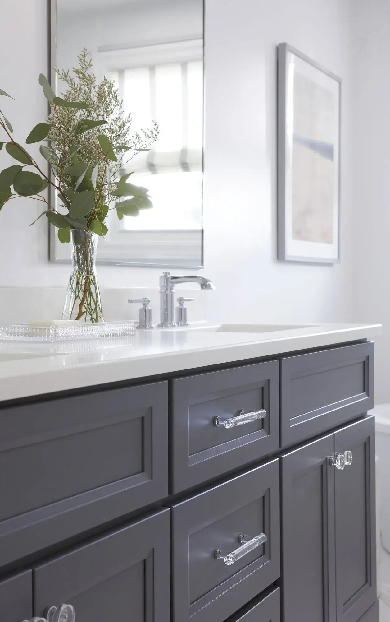 Dark vanity and stone countertop bathroom remodel with chrome fixtures, drawers, and bright wall mirror in Richmond Hill.