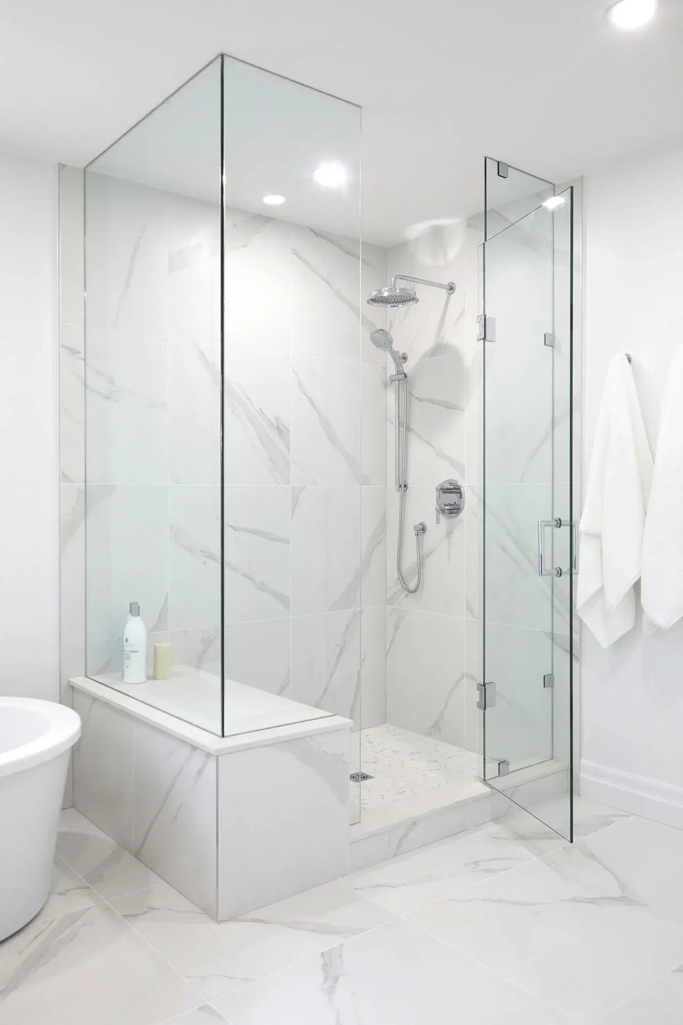 Glass shower and freestanding tub bathroom renovation with marble tile, rain shower, and bright window in Markham.