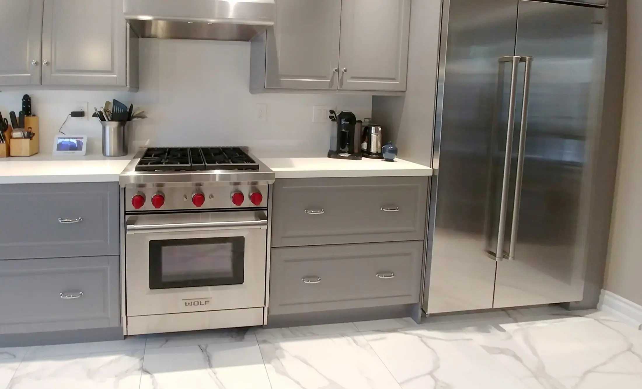 Grey shaker kitchen with professional range, stainless refrigerator, quartz counters, and marble-look floor in Vaughan.