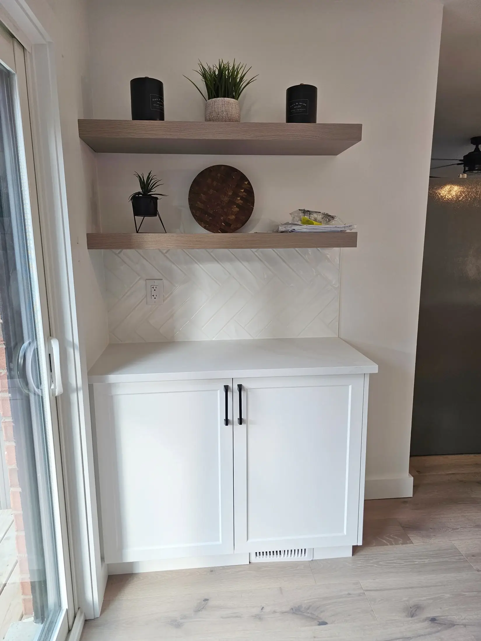 Kitchen coffee bar with floating shelves, herringbone backsplash, white lower cabinets, and warm wood accents in Toronto.