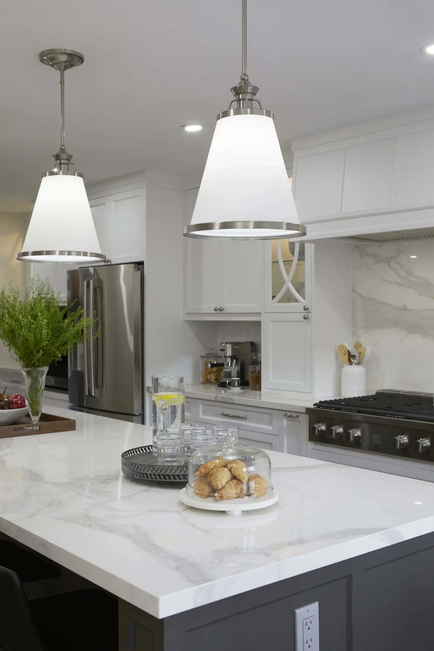 Close-up of kitchen island pendant lights, quartz countertop, white cabinetry, and stainless appliances in Vaughan.