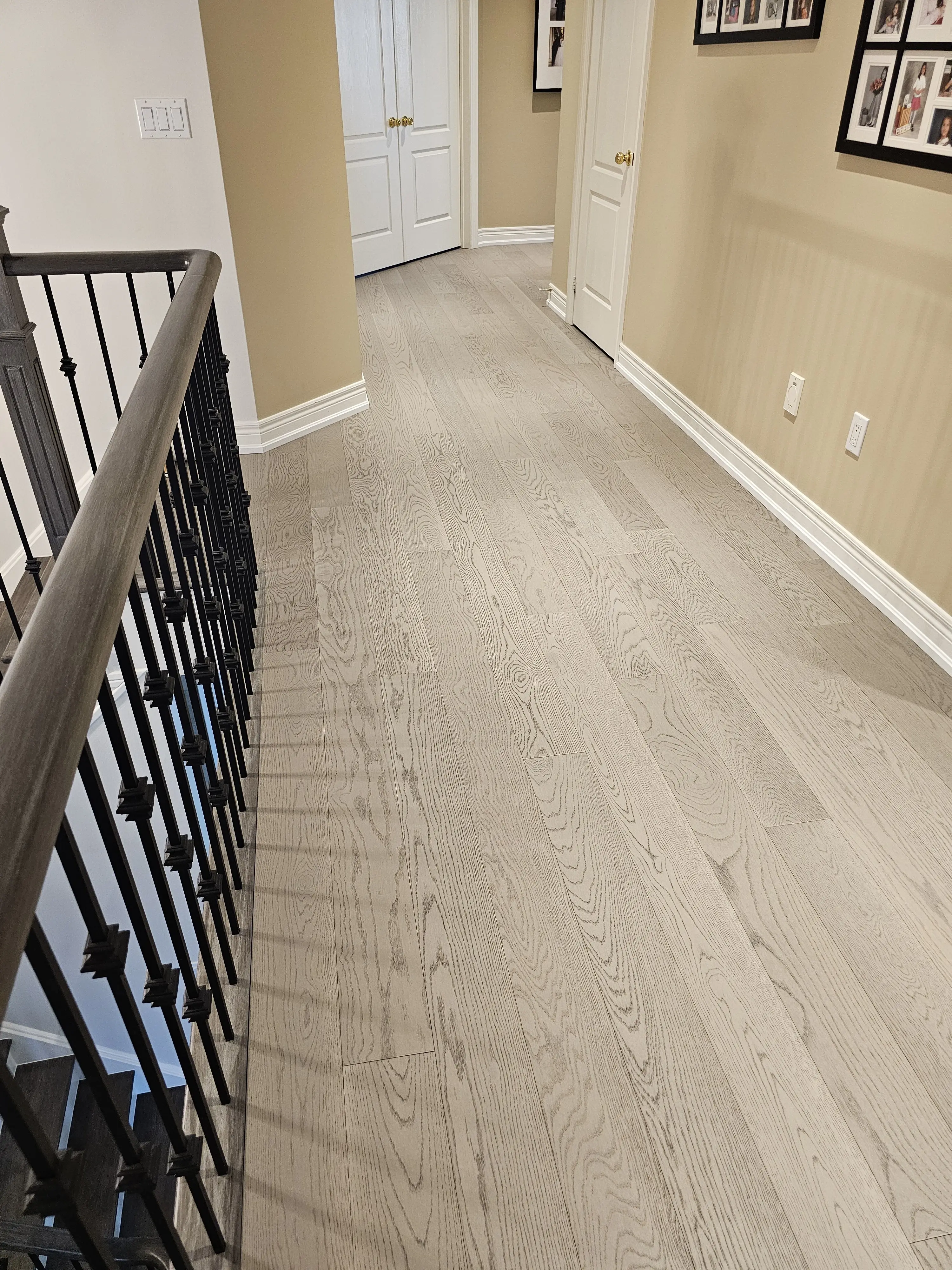 Light oak hardwood flooring beside a stair railing and finished trim.