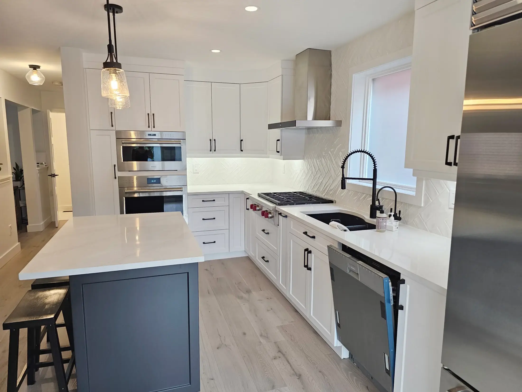 Shaker style kitchen cabinets with herringbone backsplash and professional stainless appliances in Georgetown.
