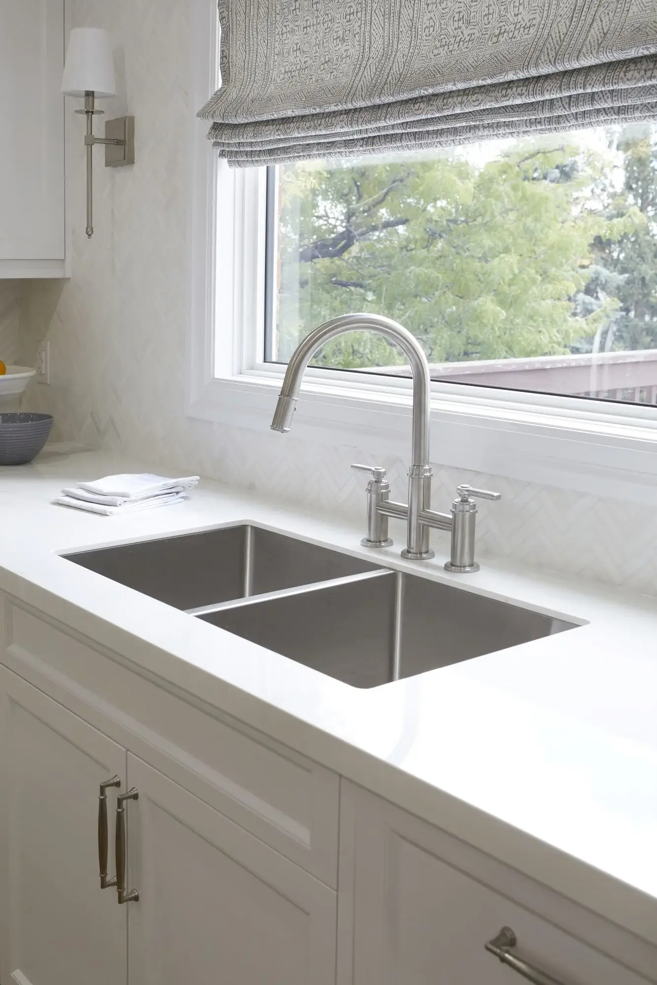 Stainless steel sink with black faucet in a white kitchen with quartz countertops in Vaughan.