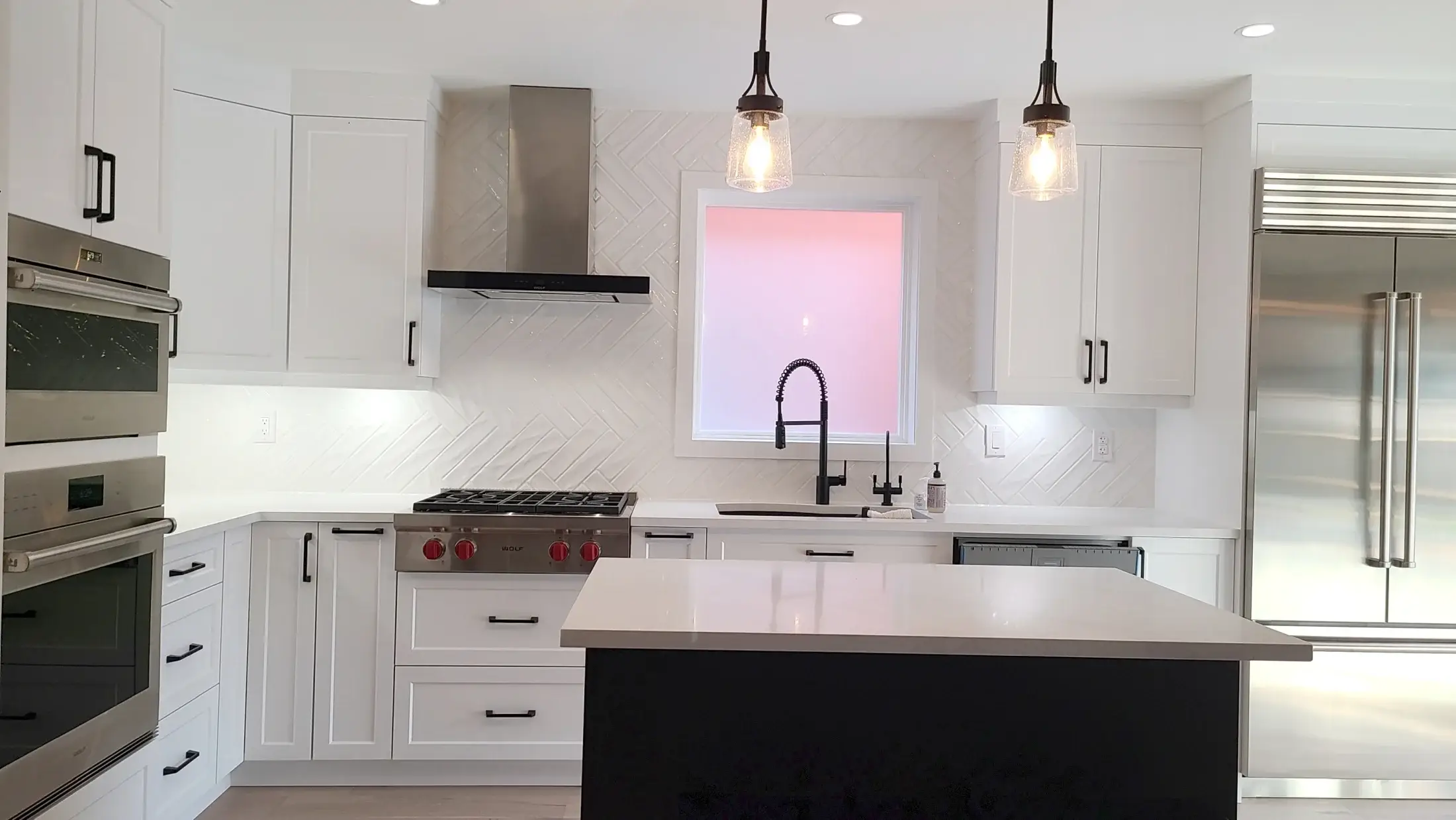 Two-tone kitchen island with black base, quartz countertop, pendant lighting, and white shaker cabinets in Vaughan.