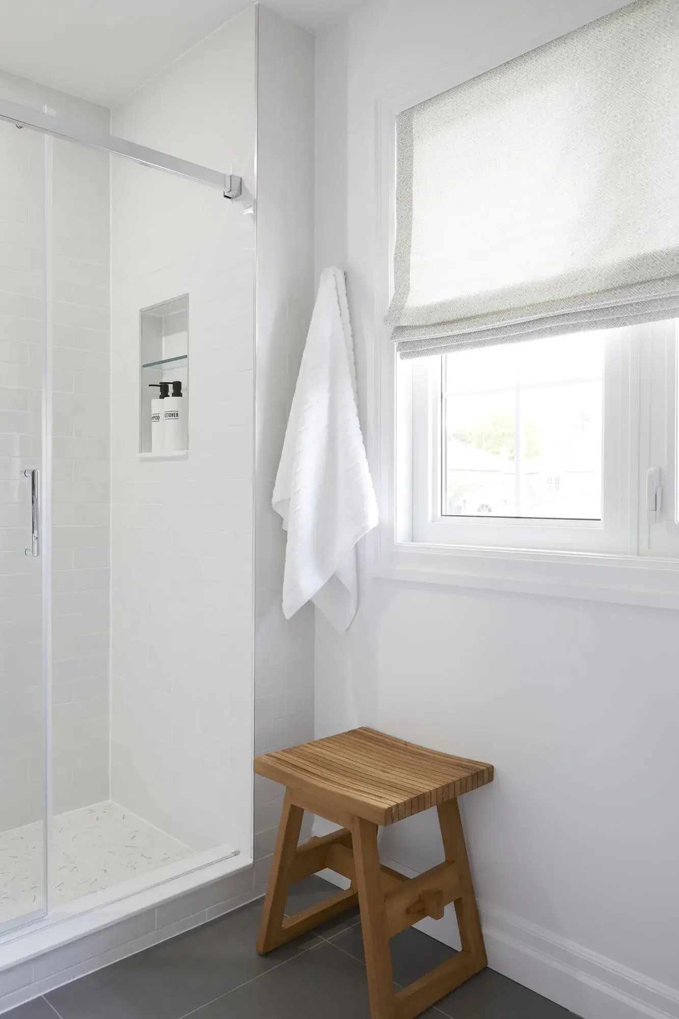 Walk-in shower bathroom renovation with window, frameless glass, marble tile, and bright white finishes in Toronto.