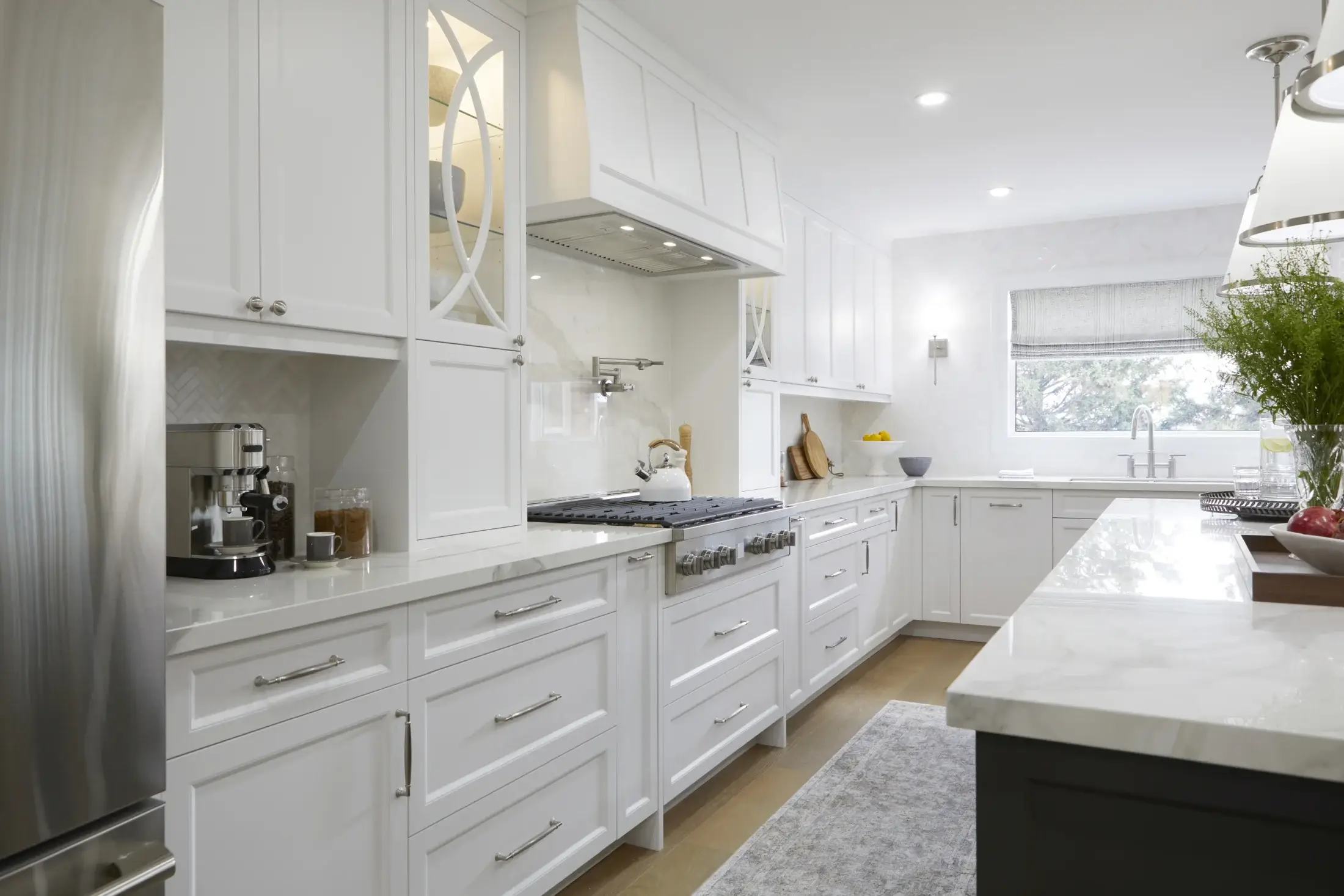 Custom white kitchen cabinets with quartz backsplash, integrated range hood, and bright finished layout in Toronto.