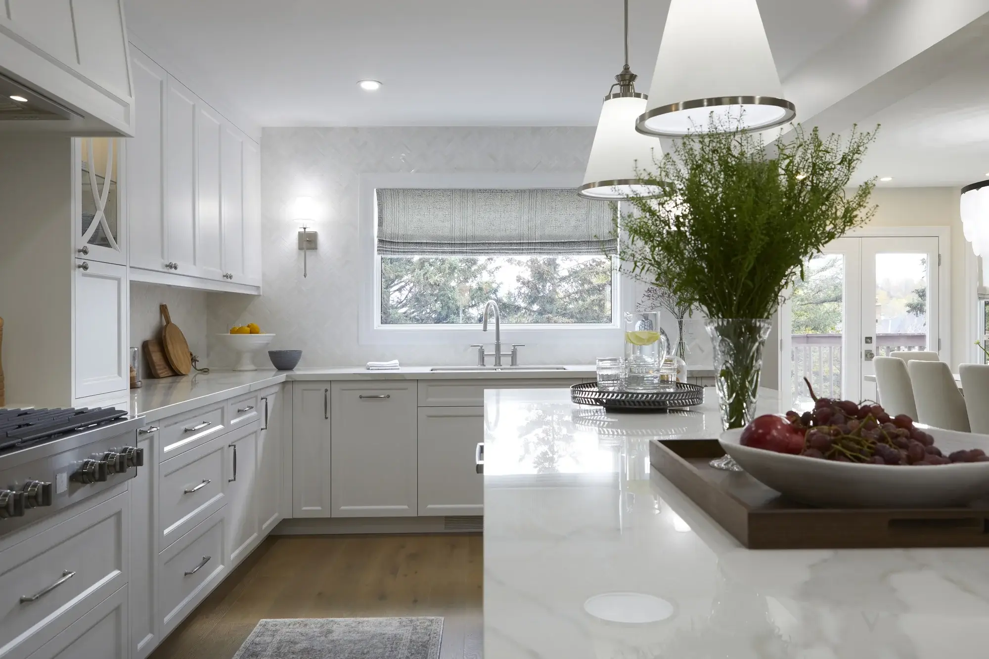 White kitchen with quartz island, sink wall, pendant lighting, herringbone backsplash, and bright open dining access in Vaughan.