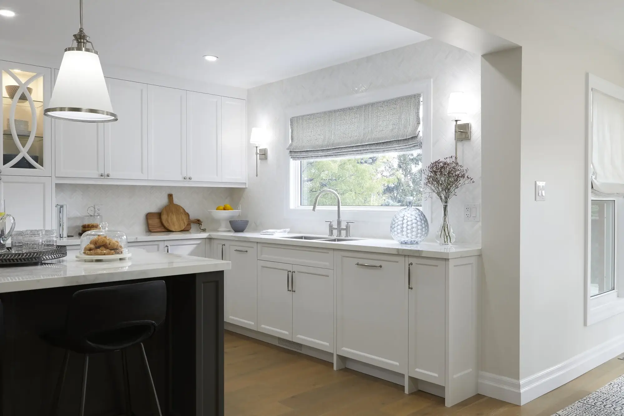 White kitchen sink wall with herringbone backsplash, quartz counters, window sconces, and custom shaker cabinets in Vaughan.