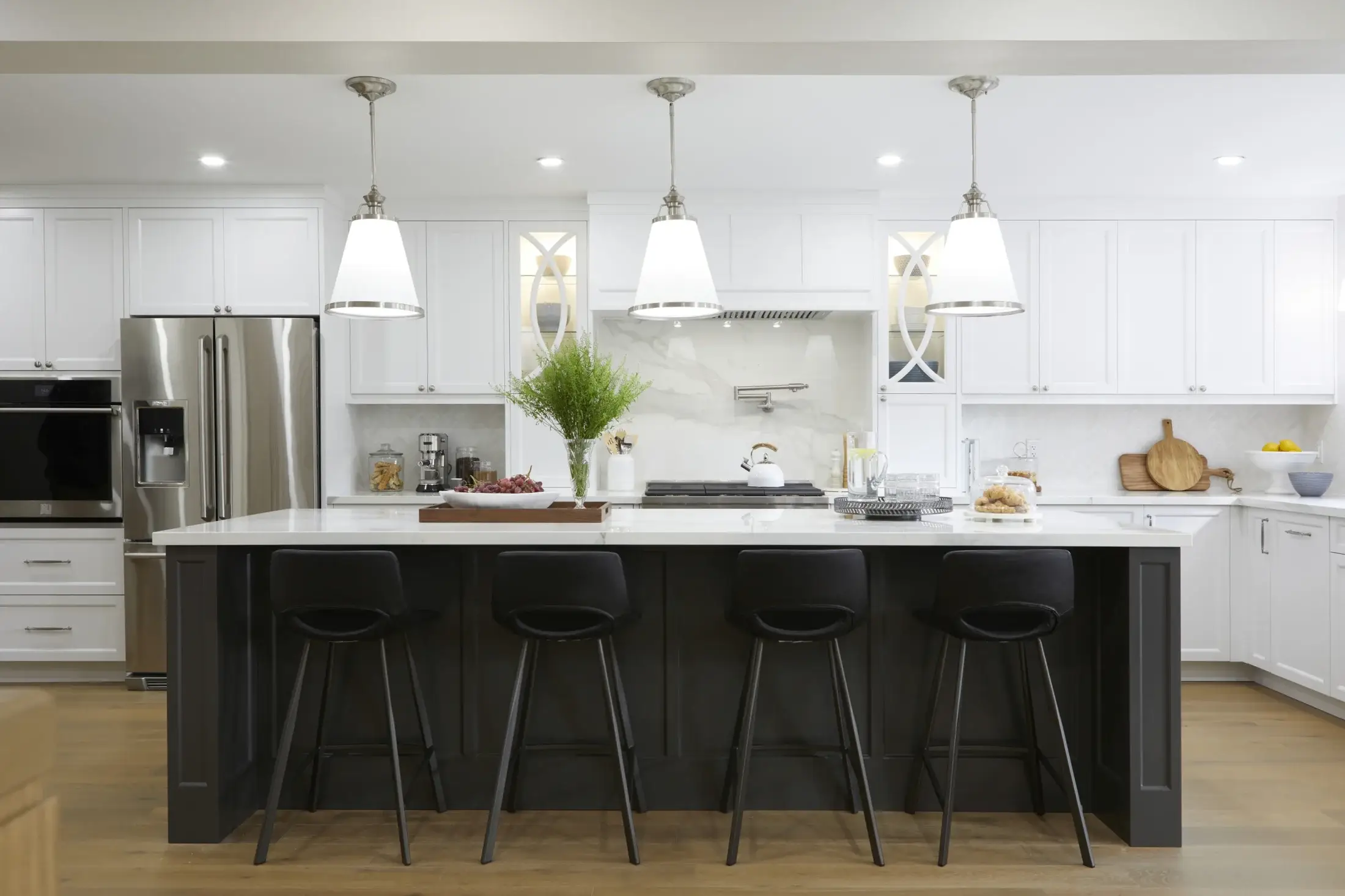 Large white shaker kitchen renovation with black island, quartz countertop, pendant lights, and stainless appliances in Vaughan.
