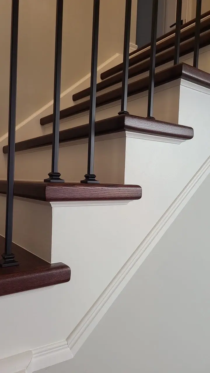 Close-up of dark-stained stair treads, white risers and black square balusters.
