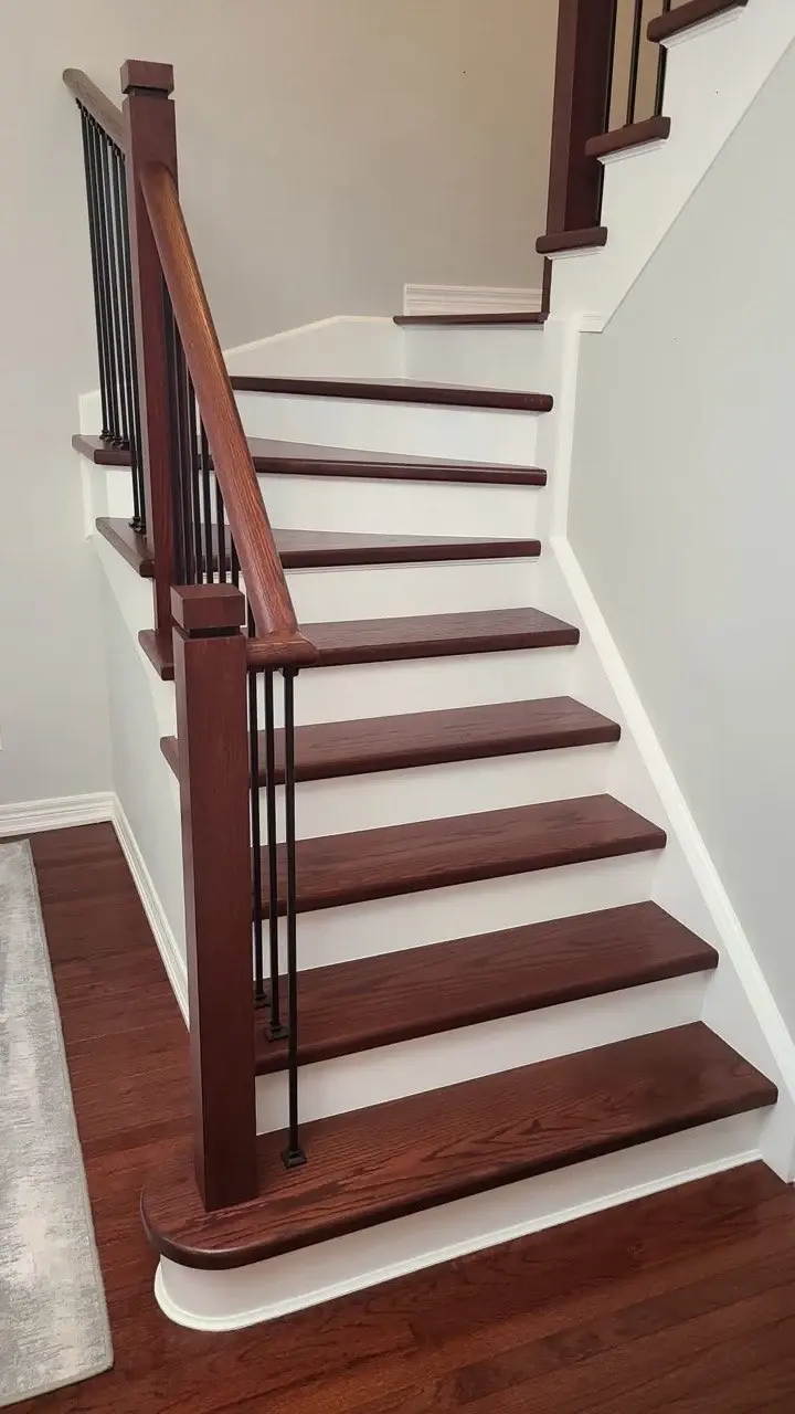 Renovated staircase with dark-stained wood treads, white risers and black metal balusters.