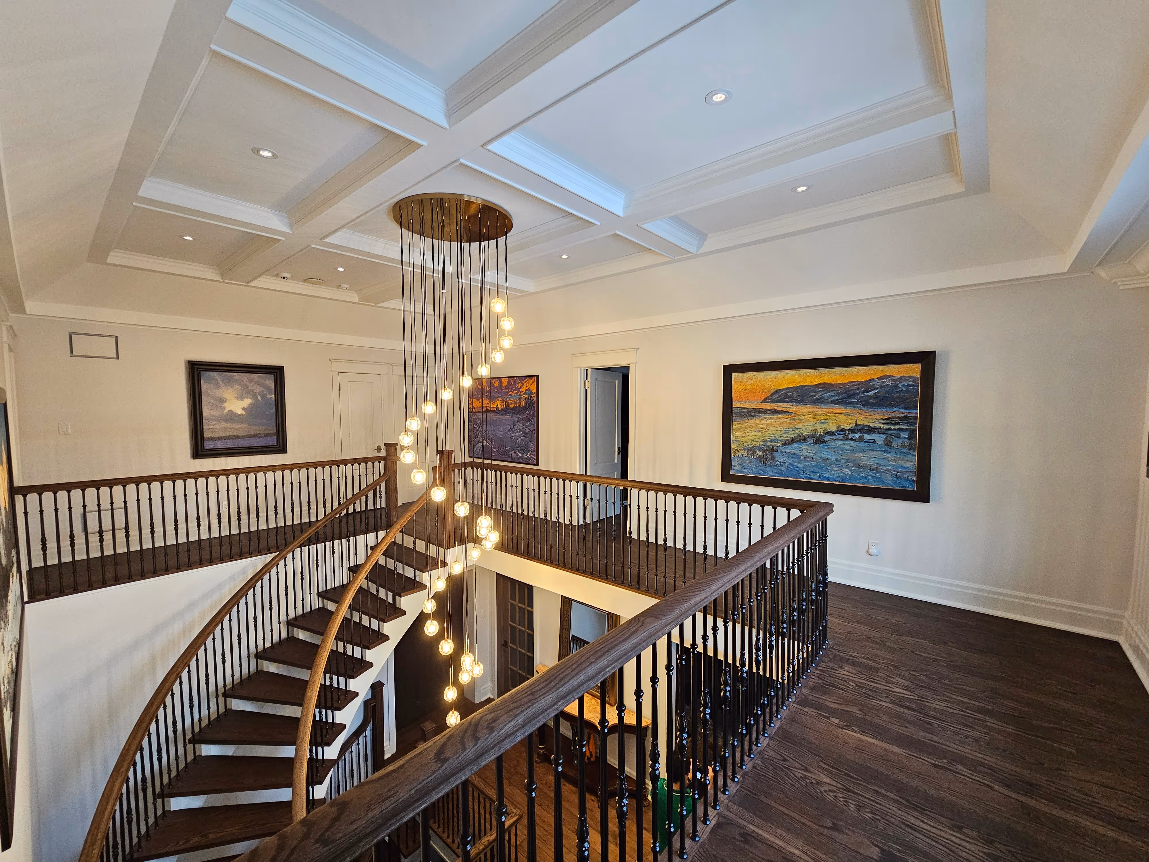 A beautifully renovated open space featuring elegant hardwood floors, decorative iron railings, and bright natural light highlighting the cozy living area and stylish decor.